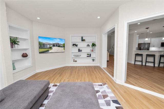 living room with built in features and light wood-type flooring