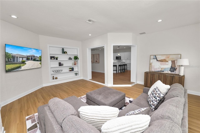 living room featuring built in shelves and hardwood / wood-style flooring