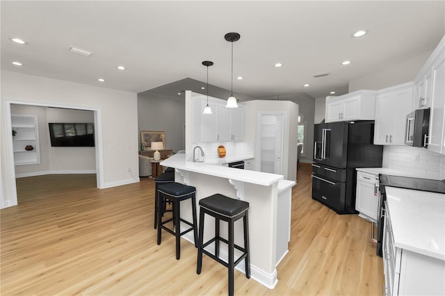 kitchen with hanging light fixtures, light hardwood / wood-style flooring, white cabinets, and appliances with stainless steel finishes