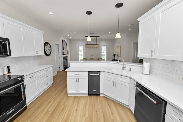 kitchen featuring decorative light fixtures, black appliances, sink, white cabinets, and kitchen peninsula