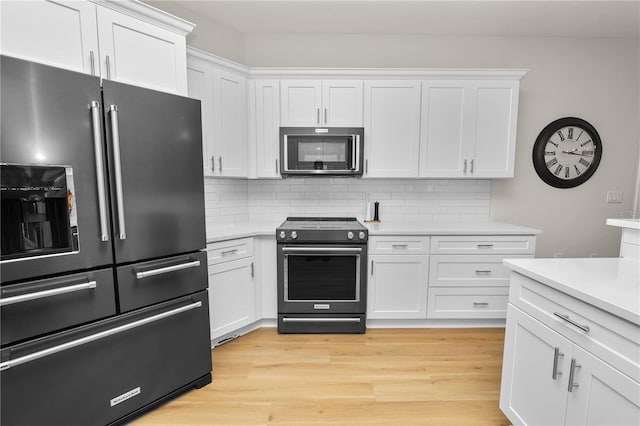 kitchen featuring range with electric stovetop, high end black refrigerator, and white cabinets