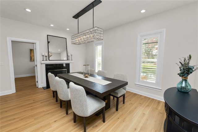 dining area with light hardwood / wood-style floors and a premium fireplace