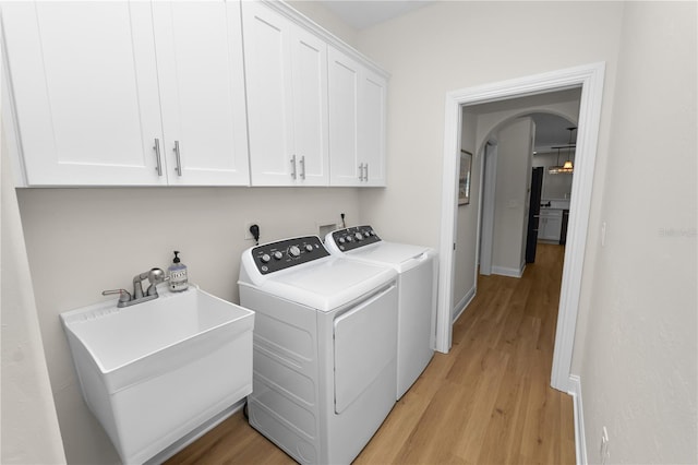 laundry room featuring cabinets, washer and clothes dryer, sink, and light wood-type flooring