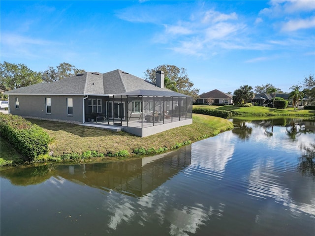 back of house with a water view, a yard, and glass enclosure