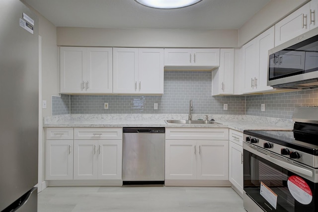 kitchen featuring appliances with stainless steel finishes, sink, white cabinets, and decorative backsplash