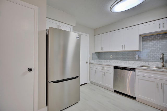 kitchen featuring stainless steel appliances, white cabinetry, sink, and backsplash