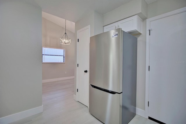 kitchen featuring white cabinetry, decorative light fixtures, light hardwood / wood-style flooring, stainless steel refrigerator, and a notable chandelier