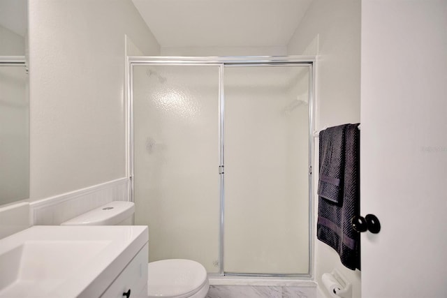 bathroom featuring vanity, a shower with shower door, and toilet