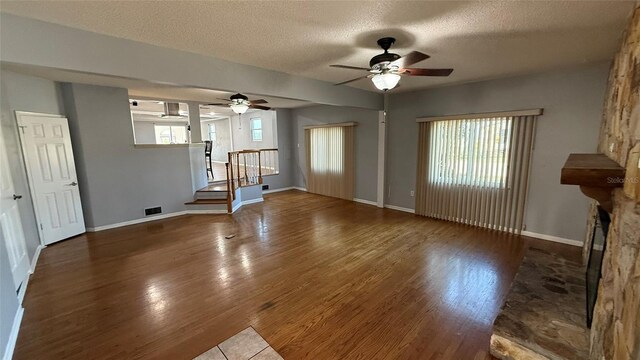 unfurnished living room with hardwood / wood-style flooring, a fireplace, and a textured ceiling