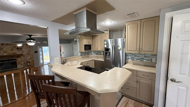 kitchen featuring black appliances, island range hood, a breakfast bar area, and kitchen peninsula