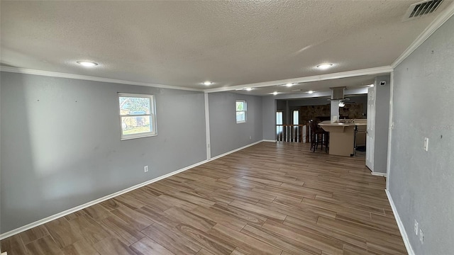 basement featuring crown molding, a textured ceiling, and light wood-type flooring