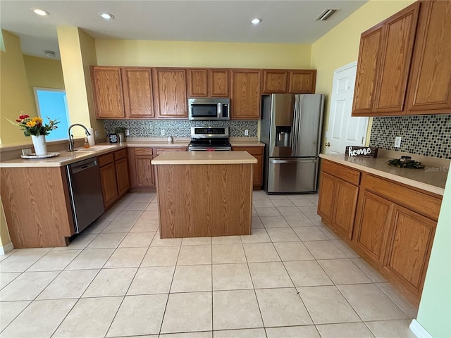 kitchen with a kitchen island, light tile patterned flooring, appliances with stainless steel finishes, and sink