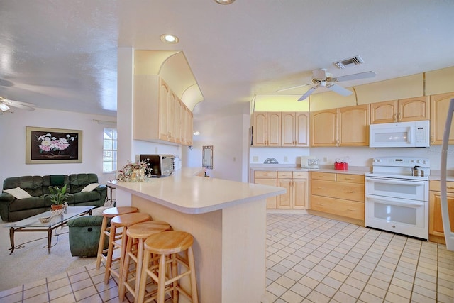 kitchen with white appliances, ceiling fan, a kitchen breakfast bar, kitchen peninsula, and light brown cabinets