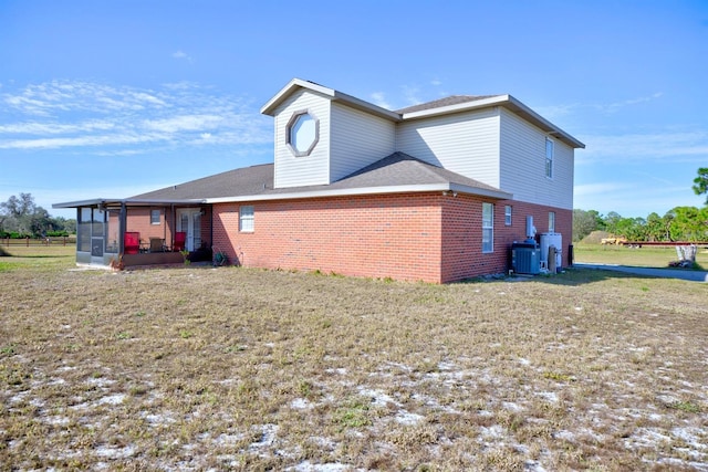 view of side of property featuring a sunroom, a yard, and central AC unit