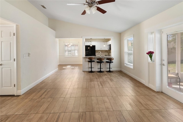 interior space with sink, a wealth of natural light, light hardwood / wood-style floors, and vaulted ceiling