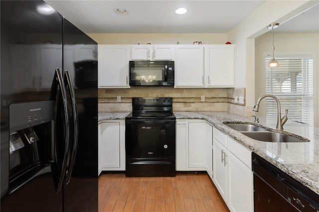 kitchen with hanging light fixtures, sink, white cabinets, and black appliances