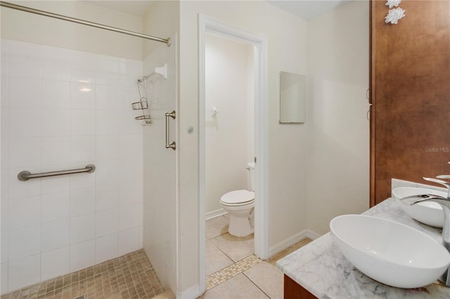 bathroom featuring vanity, toilet, tile patterned flooring, and a tile shower