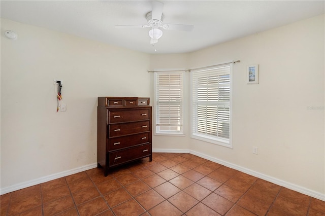 spare room with ceiling fan and dark tile patterned floors