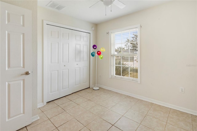 unfurnished bedroom with ceiling fan, a closet, and light tile patterned floors