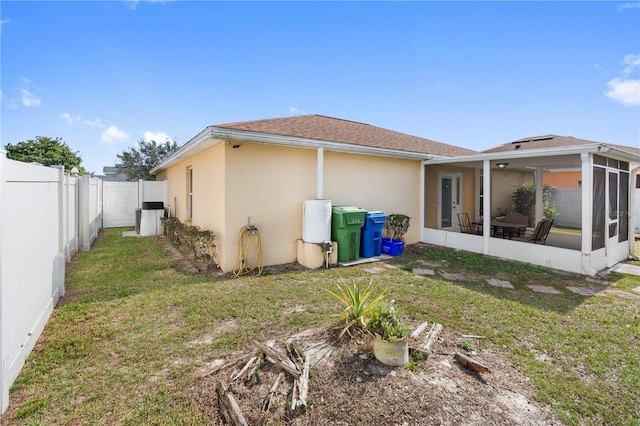 rear view of house with a lawn and a sunroom