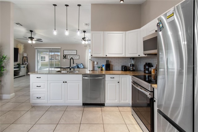 kitchen with light tile patterned flooring, sink, white cabinetry, kitchen peninsula, and stainless steel appliances