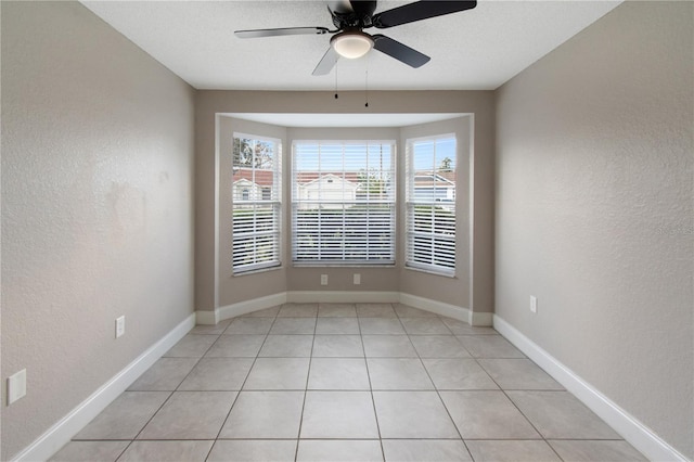 tiled empty room with ceiling fan and a textured ceiling