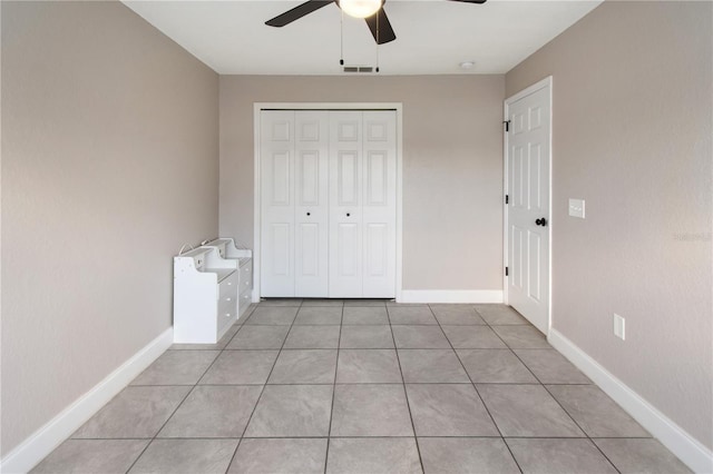 unfurnished bedroom featuring light tile patterned floors, ceiling fan, and a closet