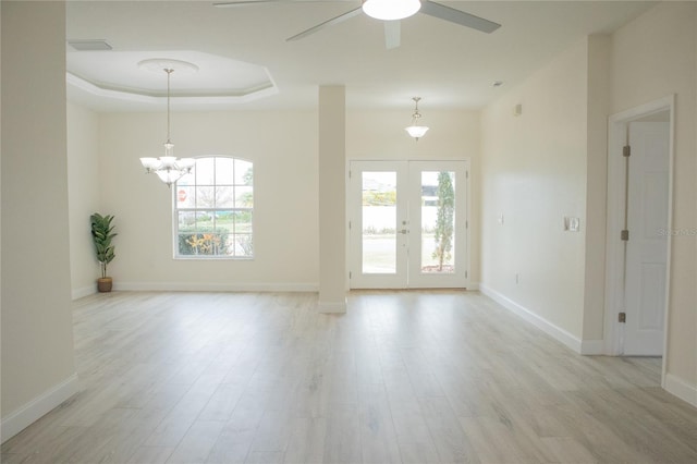 unfurnished room featuring plenty of natural light, light wood-type flooring, and a tray ceiling