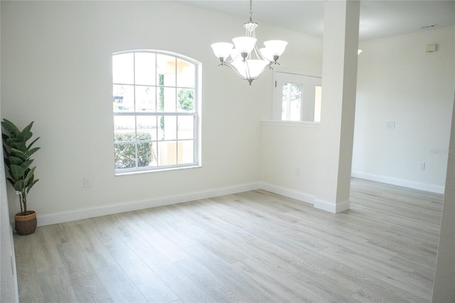 empty room with a notable chandelier and light wood-type flooring