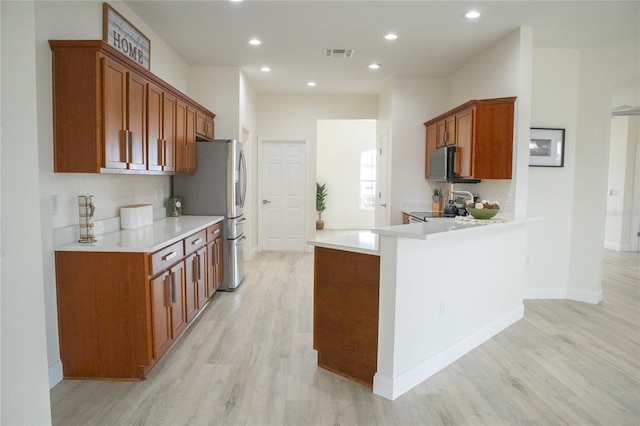 kitchen with stainless steel appliances, light hardwood / wood-style floors, and kitchen peninsula