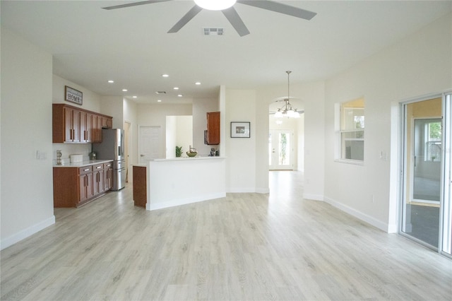 unfurnished living room featuring ceiling fan with notable chandelier and light wood-type flooring