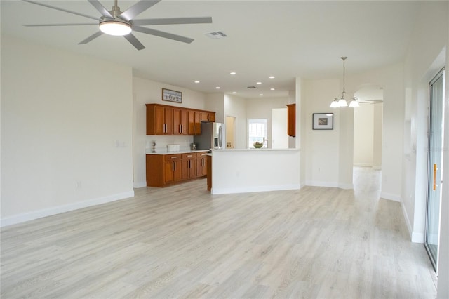 unfurnished living room with ceiling fan with notable chandelier and light hardwood / wood-style flooring