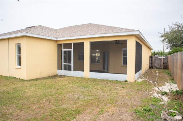 back of property with a yard, a sunroom, and ceiling fan