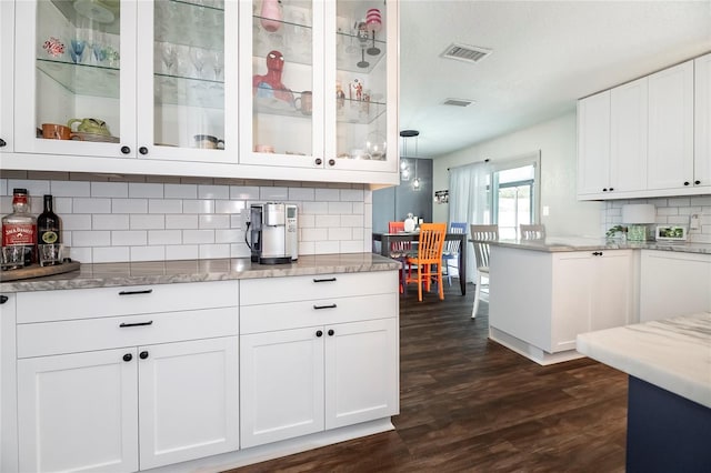 kitchen featuring decorative light fixtures, dark hardwood / wood-style floors, white cabinets, light stone countertops, and backsplash