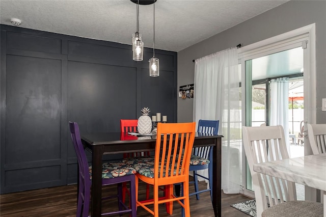 dining space featuring dark wood-type flooring and a textured ceiling