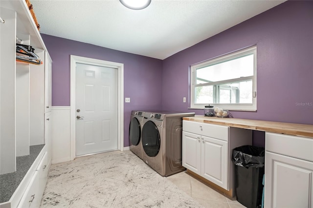 clothes washing area with cabinets, a textured ceiling, and washer and clothes dryer