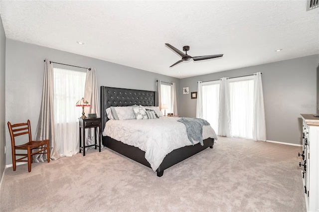 carpeted bedroom featuring ceiling fan and a textured ceiling