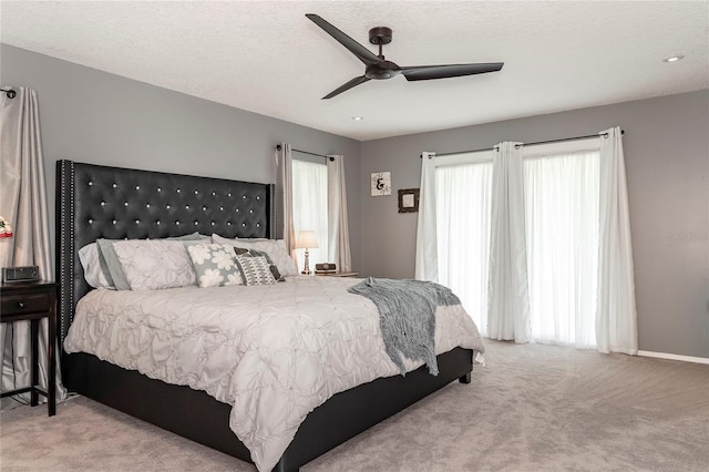 carpeted bedroom with ceiling fan and a textured ceiling