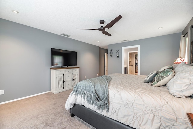 bedroom with ceiling fan, light colored carpet, and a textured ceiling