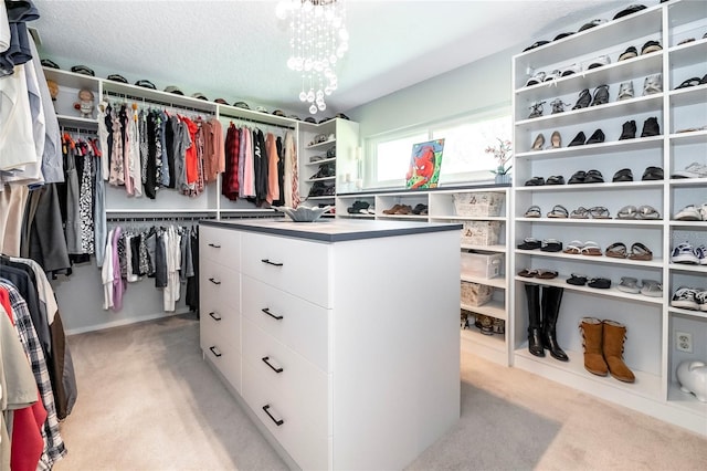 walk in closet featuring a notable chandelier and light colored carpet