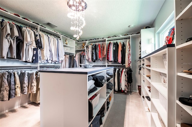 walk in closet featuring an inviting chandelier and light colored carpet