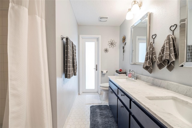 bathroom with vanity, walk in shower, toilet, tile patterned floors, and a textured ceiling