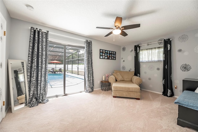 living area featuring ceiling fan, light colored carpet, and a textured ceiling