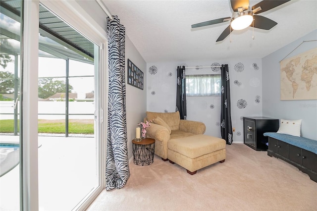 sitting room featuring ceiling fan, light carpet, and a textured ceiling