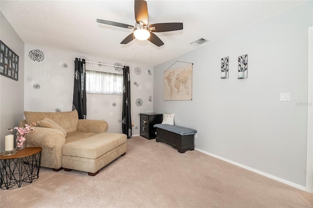 living area featuring ceiling fan, carpet flooring, and a textured ceiling