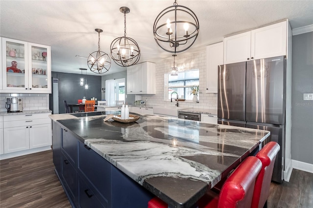 kitchen featuring dark wood-style flooring, a sink, freestanding refrigerator, and white cabinetry