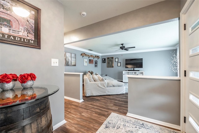 living room with ornamental molding, ceiling fan, dark wood-type flooring, and baseboards