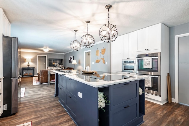 kitchen with appliances with stainless steel finishes, dark wood-type flooring, open floor plan, white cabinetry, and a kitchen island