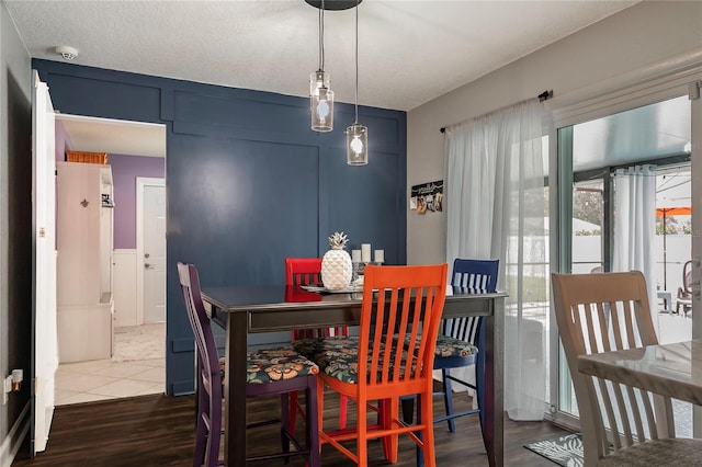 dining space featuring a textured ceiling, a decorative wall, and wood finished floors