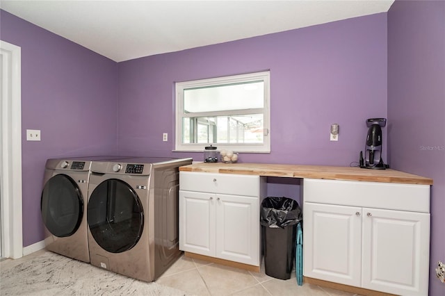 clothes washing area with cabinet space, washing machine and clothes dryer, and light tile patterned floors